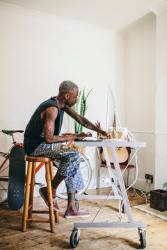 Black young man with tattoos working at his desk.