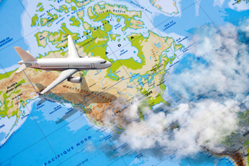 Fototapeta na wymiar avion miniature survolant carte des usa avec nuages