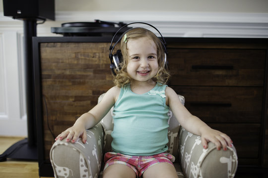 Cute toddler listening to music with big headphones
