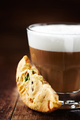 Glass of latte coffee and pistachio cookie on wooden background 