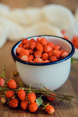 fresh wild strawberries in a Cup in the shape of a heart, symbol of love. Wooden background. The view from the top