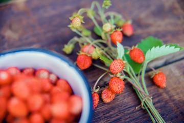 Wild strawberries in a white mug on the rustic board, organic food