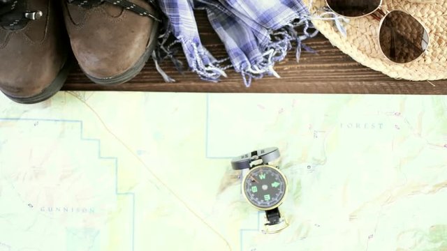 Hiking shoes with topo map and compass on a wood background