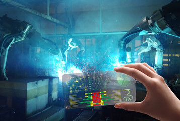 Obraz premium man use the transparent phone with the latest technology with holography and watch the technology, future and futuristic technology control Robot welding movement for Industrial automotive