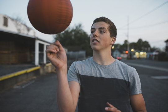 Teenage boy spinning basketball on his finger outside
