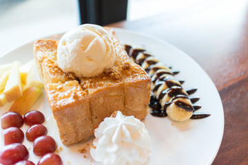 Honey toast with vanilla ice cream, whipped cream and chocolate syrup. Served with banana, grape and apple(selective focus)