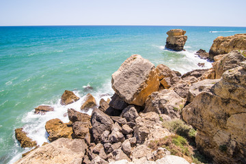 Fototapeta na wymiar Waves break about rocks the atlantic ocean at the coast of portugal. summer vocation concept
