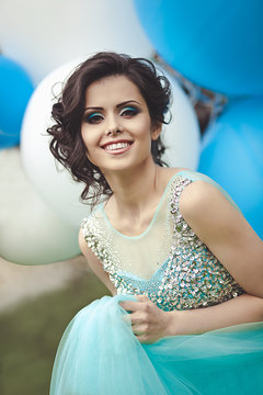 Happy Girl In Prom With Helium Air Balloons. Portrait Of A Beautiful Girl Graduate In A Blue Dress.