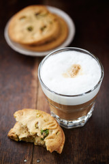 Glass of latte coffee and pistachio cookie on wooden background 