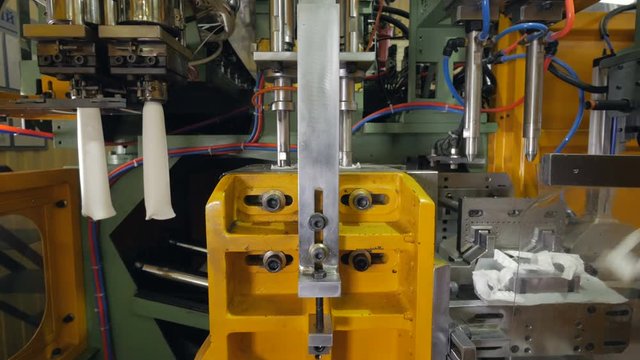 Industrial equipment making plastic containers at a plant.