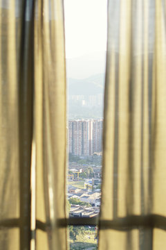 Peek through curtains over Medellin city scape high rise in Colombia