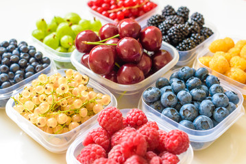 Collage of different fruits and berries isolated on white. Blueberries, cherries, blackberries, grapes, strawberries, currants. Collection of fruits and berries in a bowl. Top view