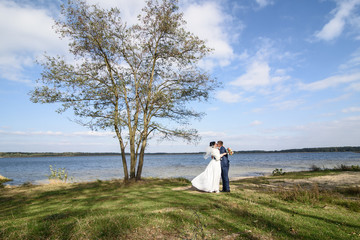 Horizontal photo of a gorgeous newlywed couple posing near the lake