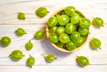 Gooseberry in wooden bowl on white wooden background. Top view with copy space