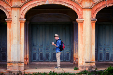 Fototapeta na wymiar An adult handsome man touring in ancient architecture French style village in Tharae Sakon Nakhon