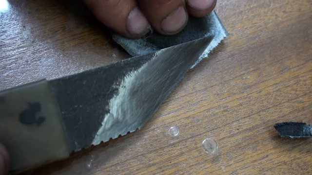 a shoemaker cleans a special knife black leather patch.
