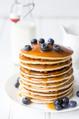 Cinnamon Pancake Stack with Blueberries and Caramel Syrup on the Crisp White Background Wooden Table and Bottle of Milk and White Plate