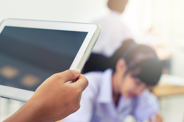 blurred of student testing in exercise, exams answer on a tablet computer in elementary, high school lesson in class room for test exams online education by finger clicking
