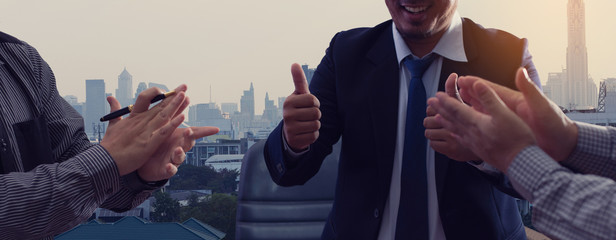 A group of happy businesspeople clapping hands and thumbs up expresses happiness and success.