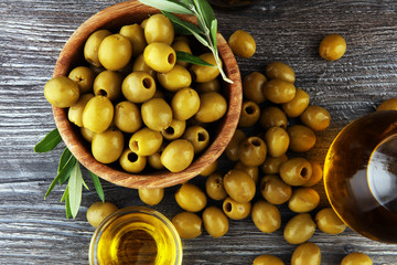 Bottle virgin olive oil and oil in a bowl with some olives