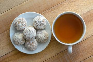 White mug with tea and cakes on the wooden table.