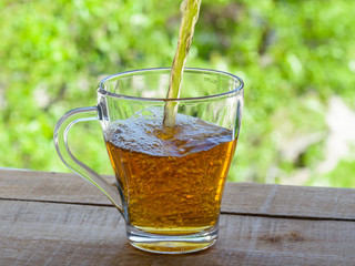 Pour drink in a glass mug on the table by the open window.
