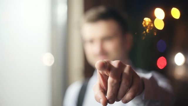 handsome man pointing finger camera focused unfocused shirt portrait closeup focused smiling confident cheerful appearance street light city lights night gesturing gesture points emotional looking guy