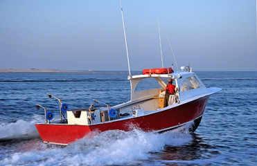 Fototapeta premium Side and rear view of red recreational fishing boat in Atlantic Ocean. North Carolina.