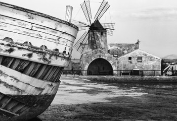 Dettagli barca in primo piano con mulino a vento sullo sfondo nella salina di Trapani