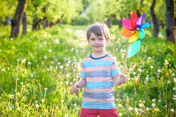Portrait of a happy cute little boy holding pinwheel at the park