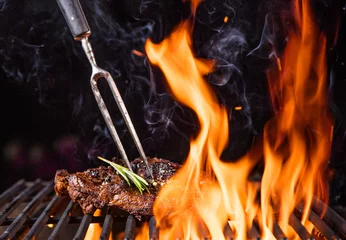 Crédence de cuisine en verre imprimé Grill / Barbecue Steaks de boeuf sur le gril avec des flammes