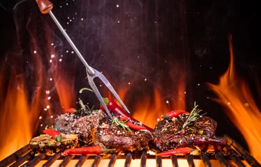 Crédence de cuisine en verre imprimé Grill / Barbecue Steaks de boeuf sur le gril avec des flammes