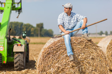 Young farmer riding a hay bale
