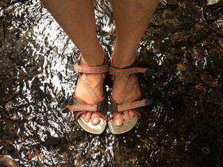 Füße stehen im flachen Wasser und kühlen ab