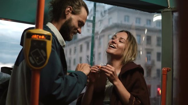 Young beautiful man and woman feeding each other the candies or sweets, having fun. Happy couple in tram.