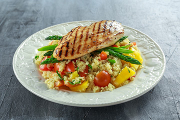 couscous salad with grilled chicken and asparagus on white plate. healthy food