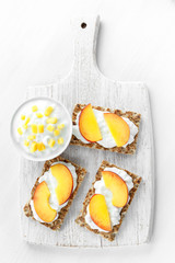 Homemade Crispbread toast with Cottage Cheese and nectarine on white wooden board.