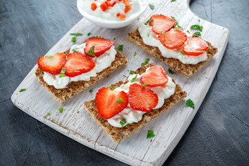 Homemade Crispbread toast with Cottage Cheese and Strawberry on white wooden board.