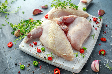 Raw Chicken breast supremes fillets with chilli, pepper corns and thyme on white wooden chopping...