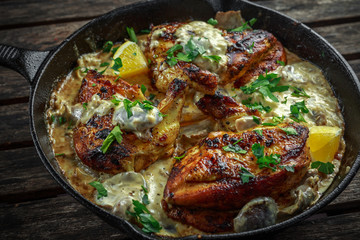 Creamy chicken fellets supremes in mushroom sauce with parsley In rustic cast iron skillet.