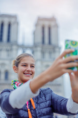 Teenager tourist girl is taking selfie with cathedral of Notre Dame de Paris. France.