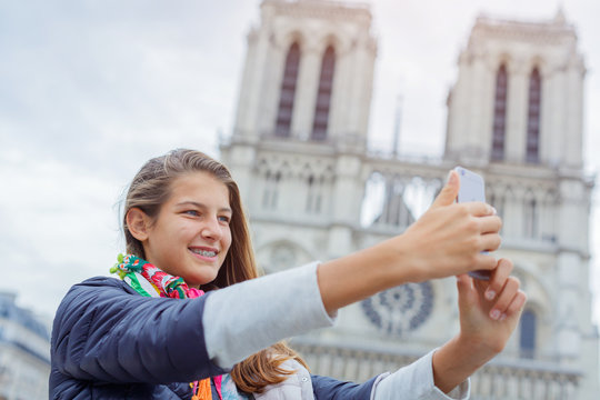 Teenager tourist girl is taking selfie with cathedral of Notre Dame de Paris. France.