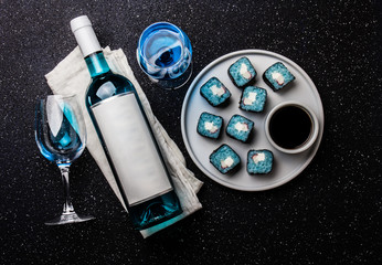 Blue sushi rolls and blue wine chardonnay on black background. Spanish blue wine, trendy drink, Fancy wine, top view. Copy space