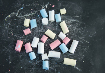 Broken colored chalk on black board background