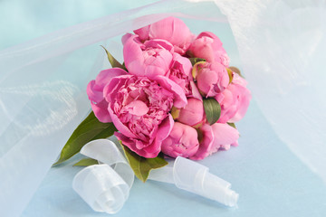 Small bouquet of pink peonies on a blue background (wedding concept)