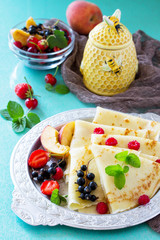 Pancake breakfast with honey and fresh berries of currants, strawberries, nectarines, sweet cherries and raspberries.