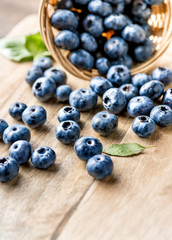 Freshly blueberries on wooden rustic wooden table. Juicy and fresh blueberries with green leaves. Bilberry on wooden background. Blueberry antioxidant. Concept for healthy eating and nutrition.