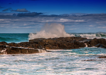 Waves breaking at rocks of the Indian Ocean at the Wild Coast of South Africa with cloudy sky