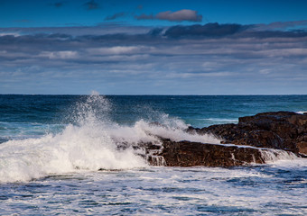 Waves breaking at rocks of the Indian Ocean at the Wild Coast of South Africa with cloudy sky