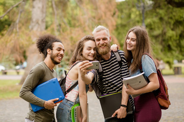 College friends making selfie on phone camera. Students walking in campus, posing for selfie.